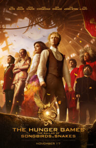 the central characters, including Lucy May and Coriolanus Snow, standing defiantly in the centre of the Hunger Games arena