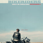 Austin Butler sits on a 60s Harley Davison motorcycle at the side of a road, looking out toward the flat horizon