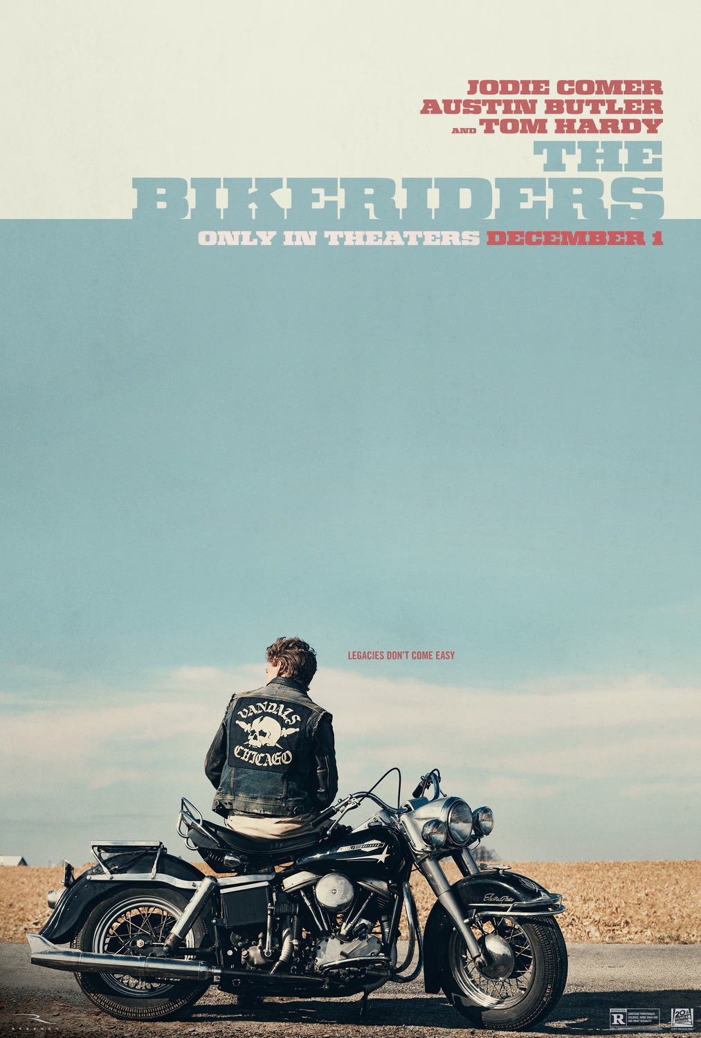 Austin Butler sits on a 60s Harley Davison motorcycle at the side of a road, looking out toward the flat horizon