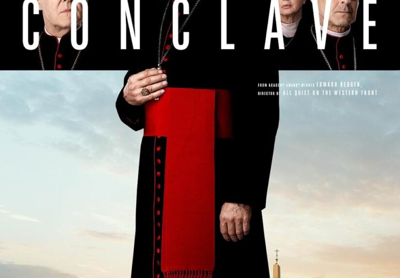 Ralph Fiennes character (a Catholic Cardinal) stands in the silhouette of the cross with the Vatican behind him. You can also see the face of other principle Cardinals in the cross.