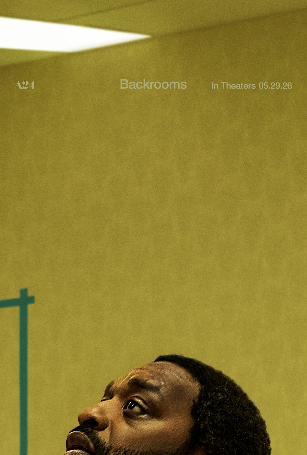 A yellow wallpapered room with the face of a man looking up cropped at the bottom of the frame