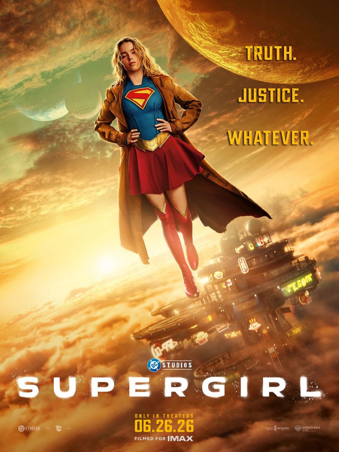 Supergirl, in her costume and brown coat hovers in front of a sunrise and alien city in the background