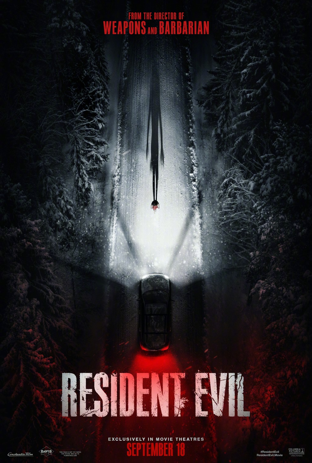 Top down view of a car driving on a snowy road toward a woman. The lights from the car subtly make up the Umbrella Corporation logo